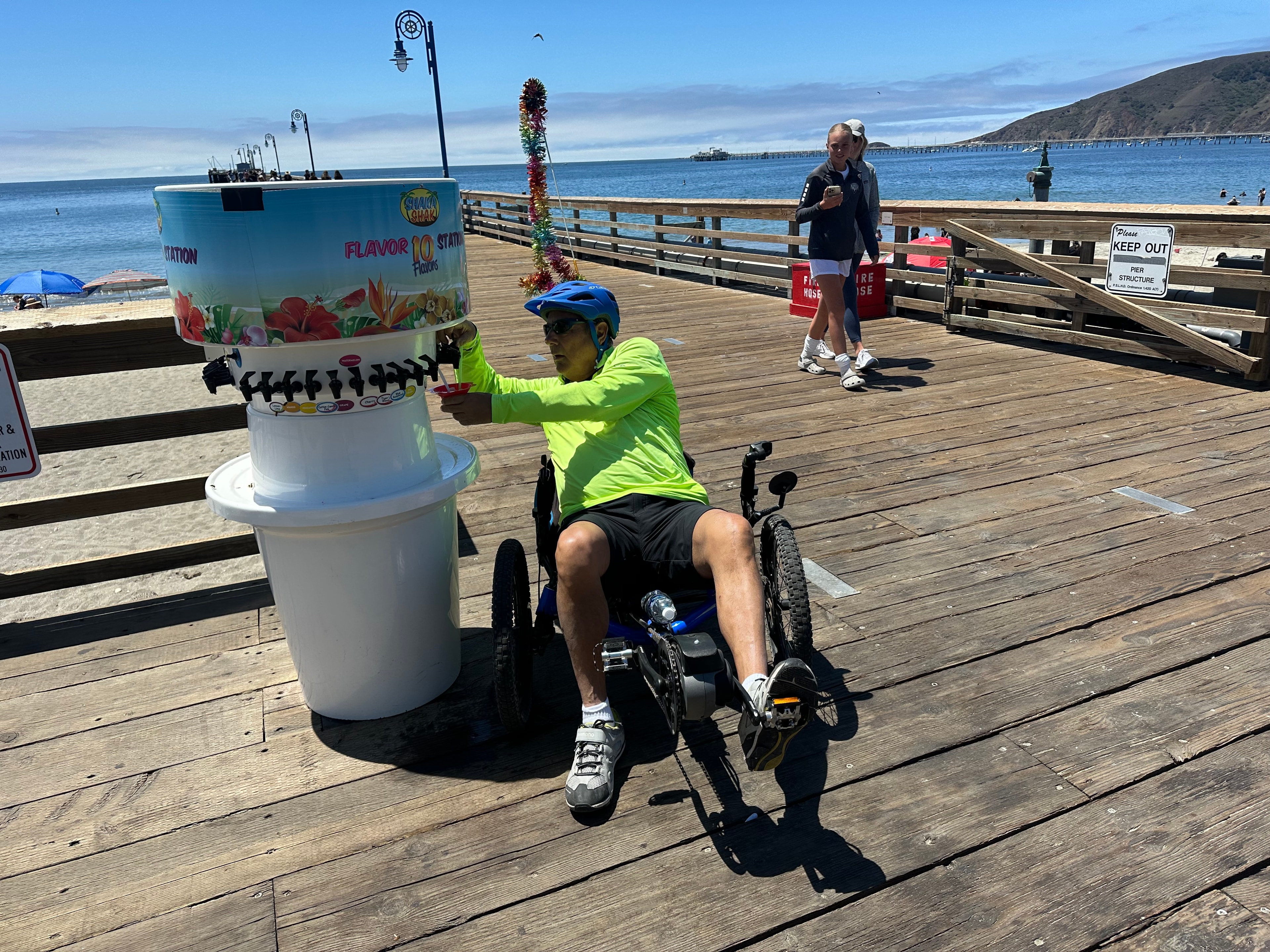 Customer on recumbent bike using the Shaka Shak flavor station on the pier