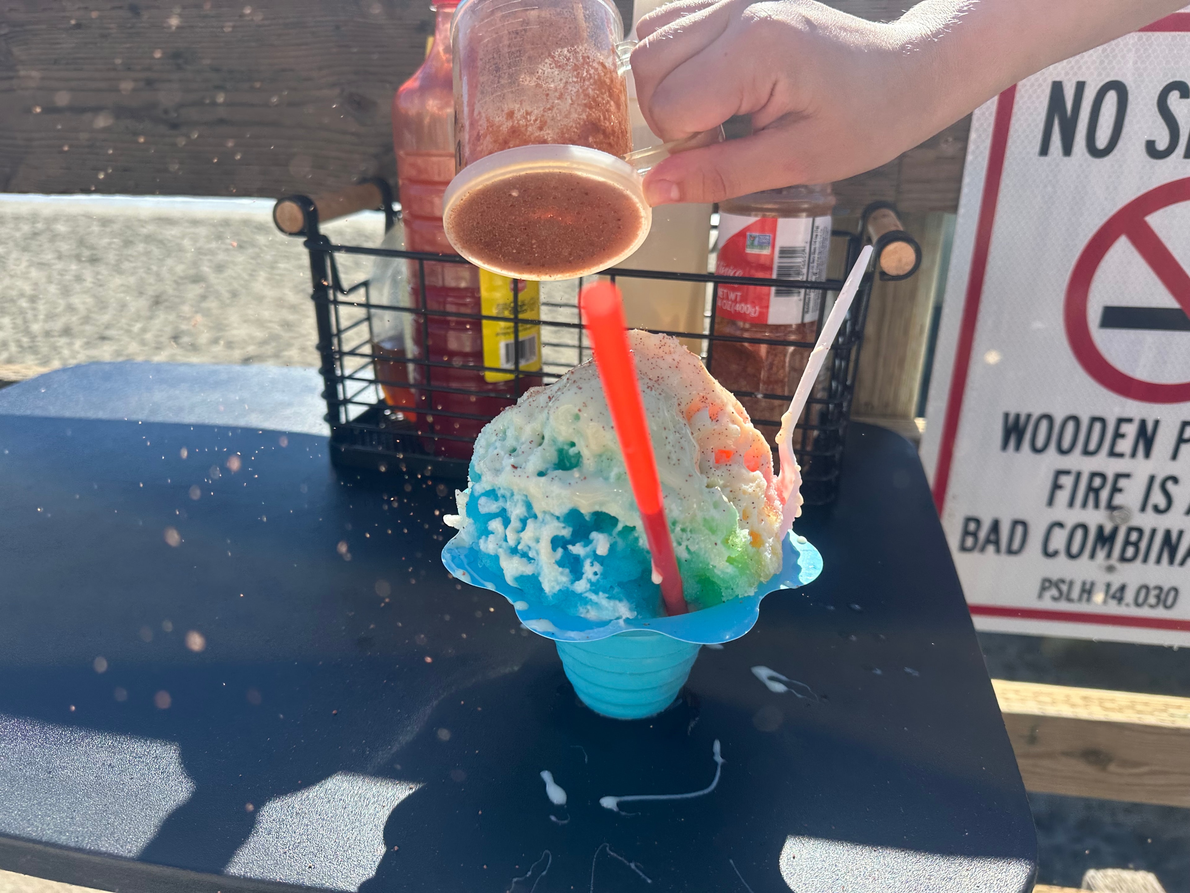 Sprinkling tajin on a colorful shave ice at the pier