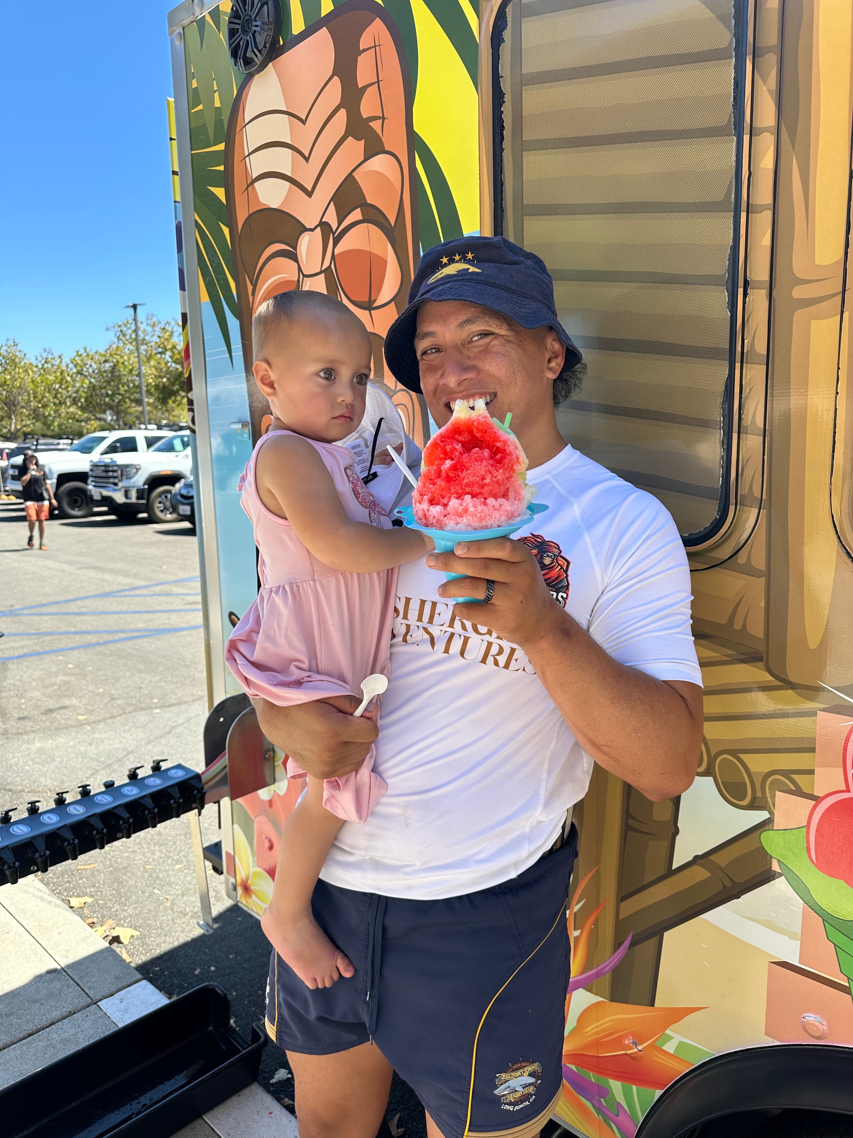Dad and baby enjoying a pink shave ice at a Shaka Shak event