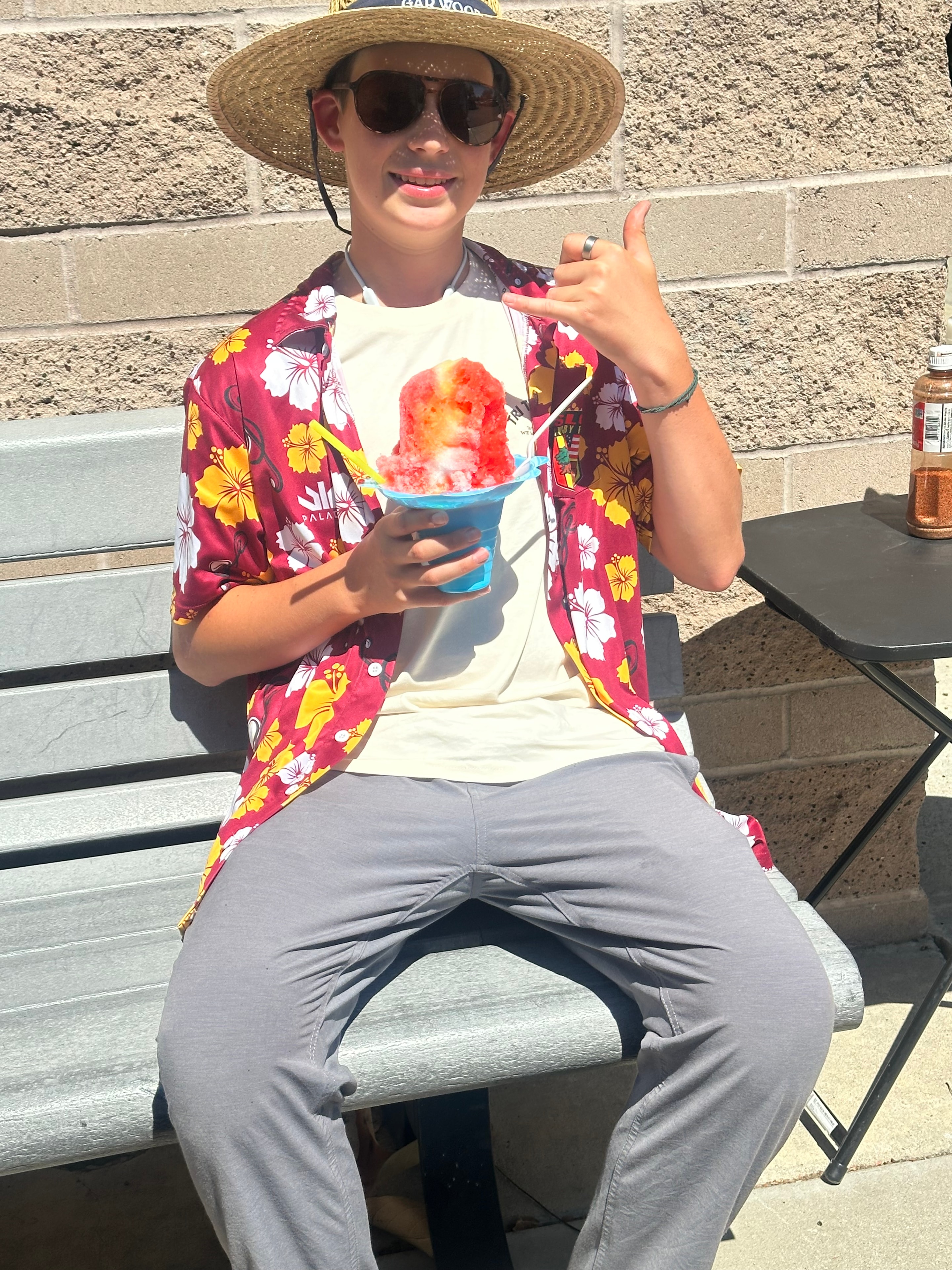 Happy customer in Hawaiian shirt holding a red shave ice