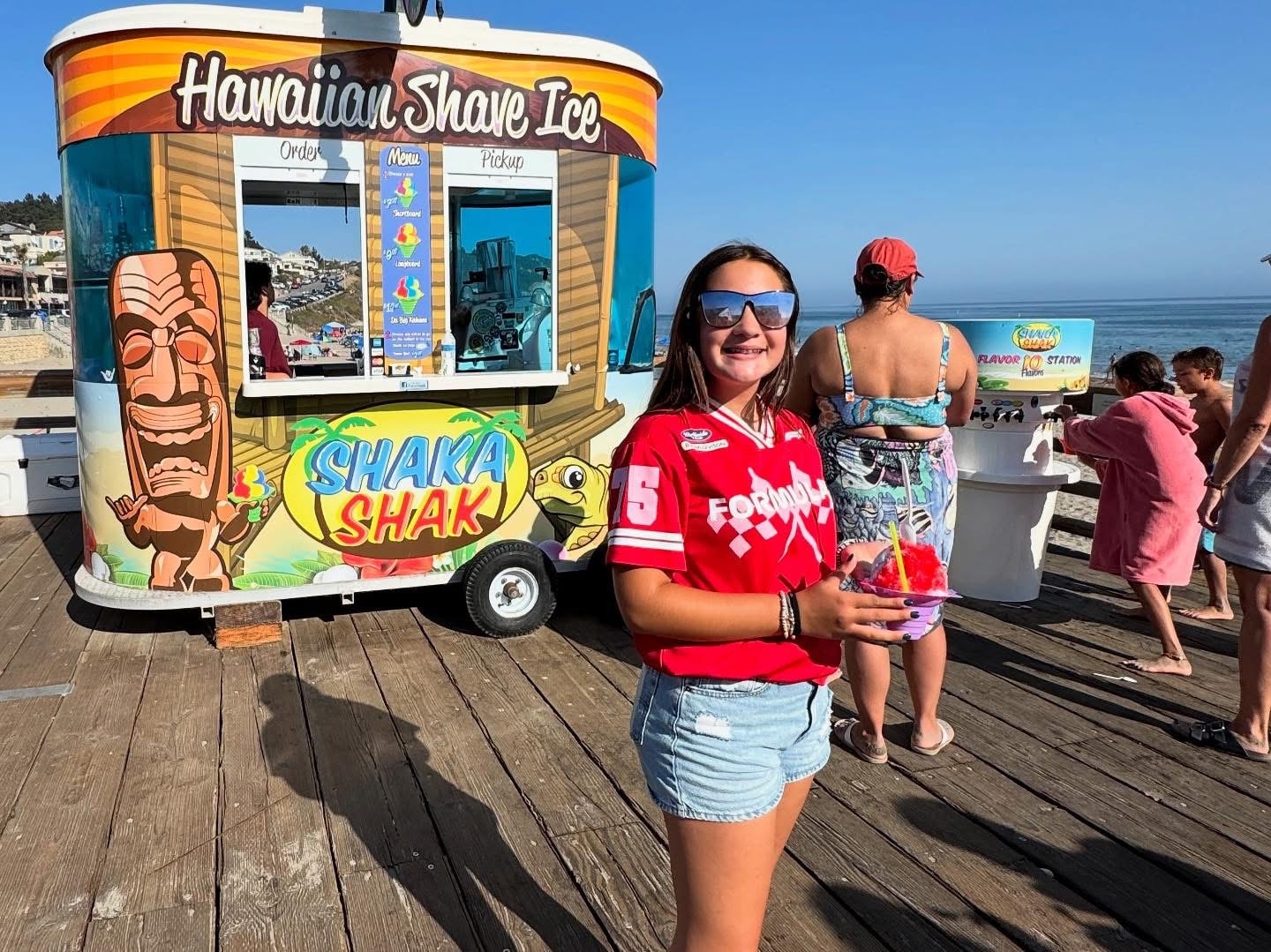 Girl smiling in front of the Shaka Shak trailer on the pier