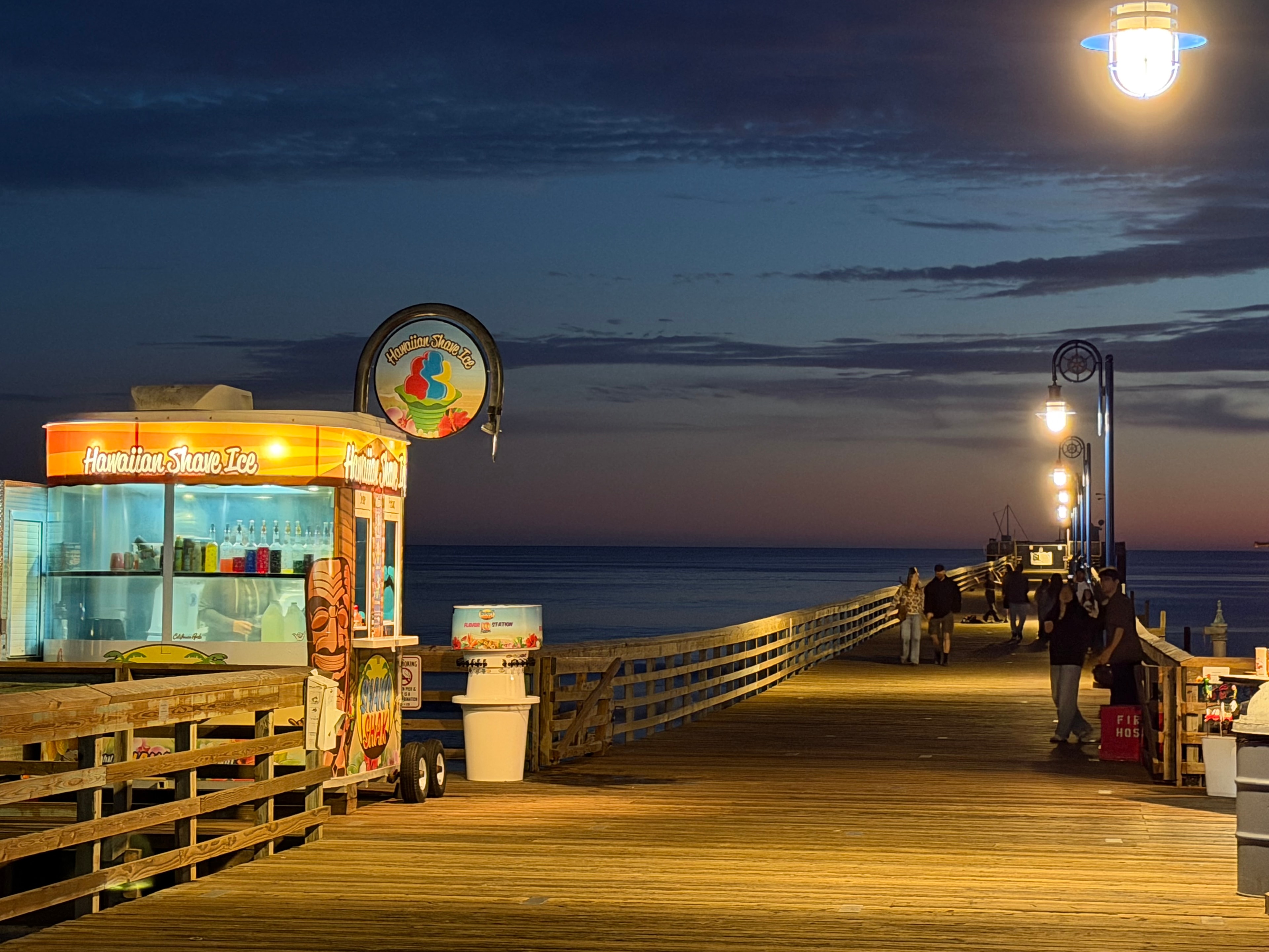 Shaka Shak Hawaiian Shave Ice kiosk lit up at night on the Avila Beach pier