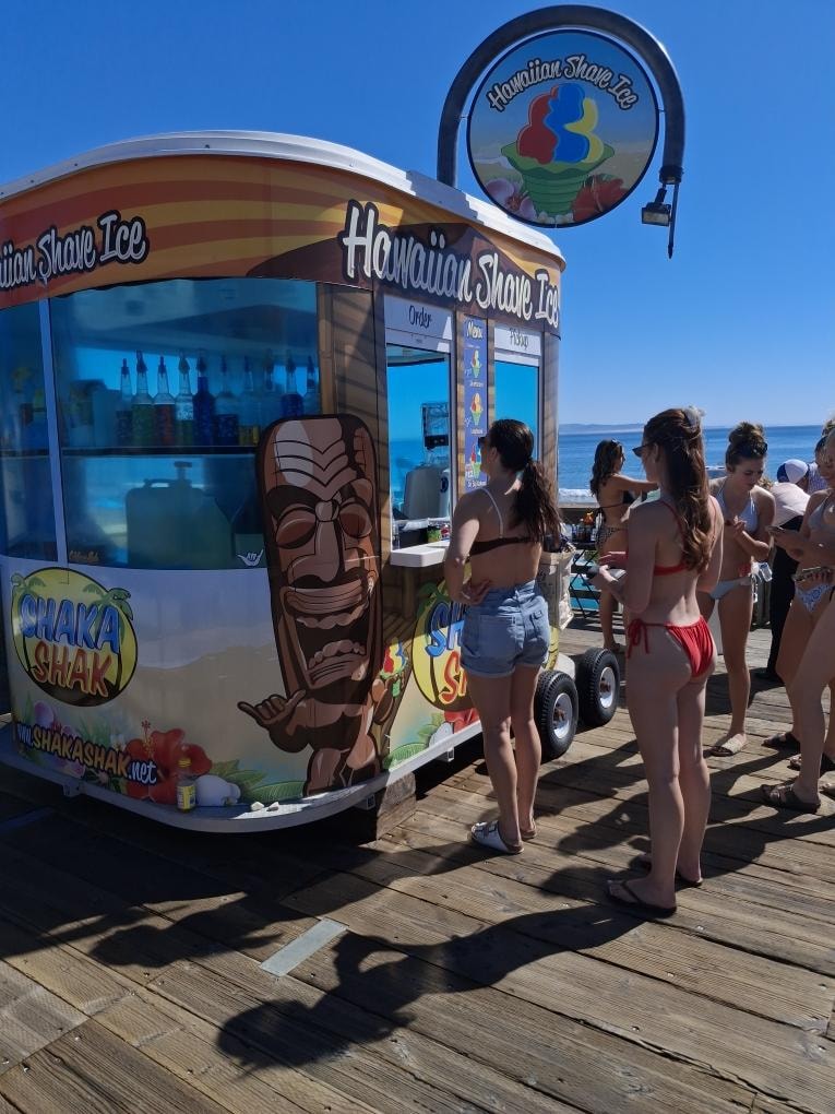 Shaka Shak kiosk on the pier with customers on a sunny day