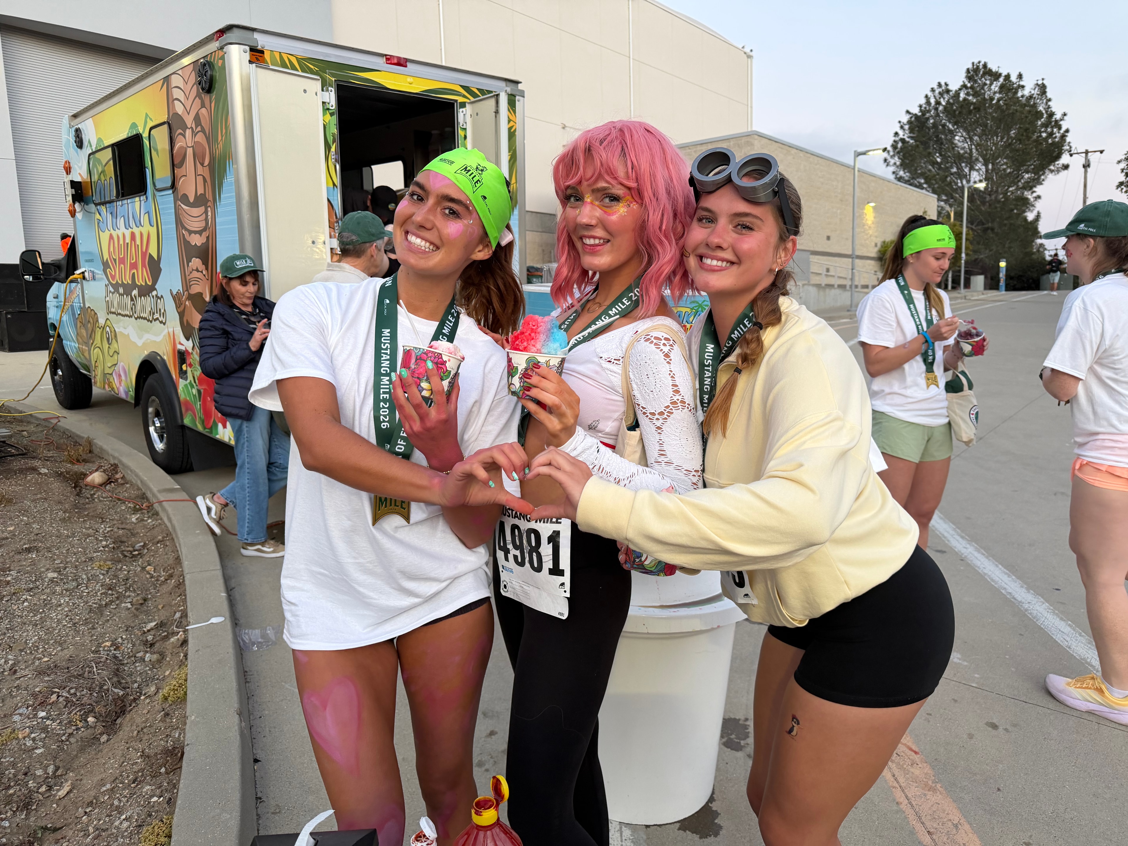 Three happy Mustang Mile runners posing with shave ice in front of the Shaka Shak truck
