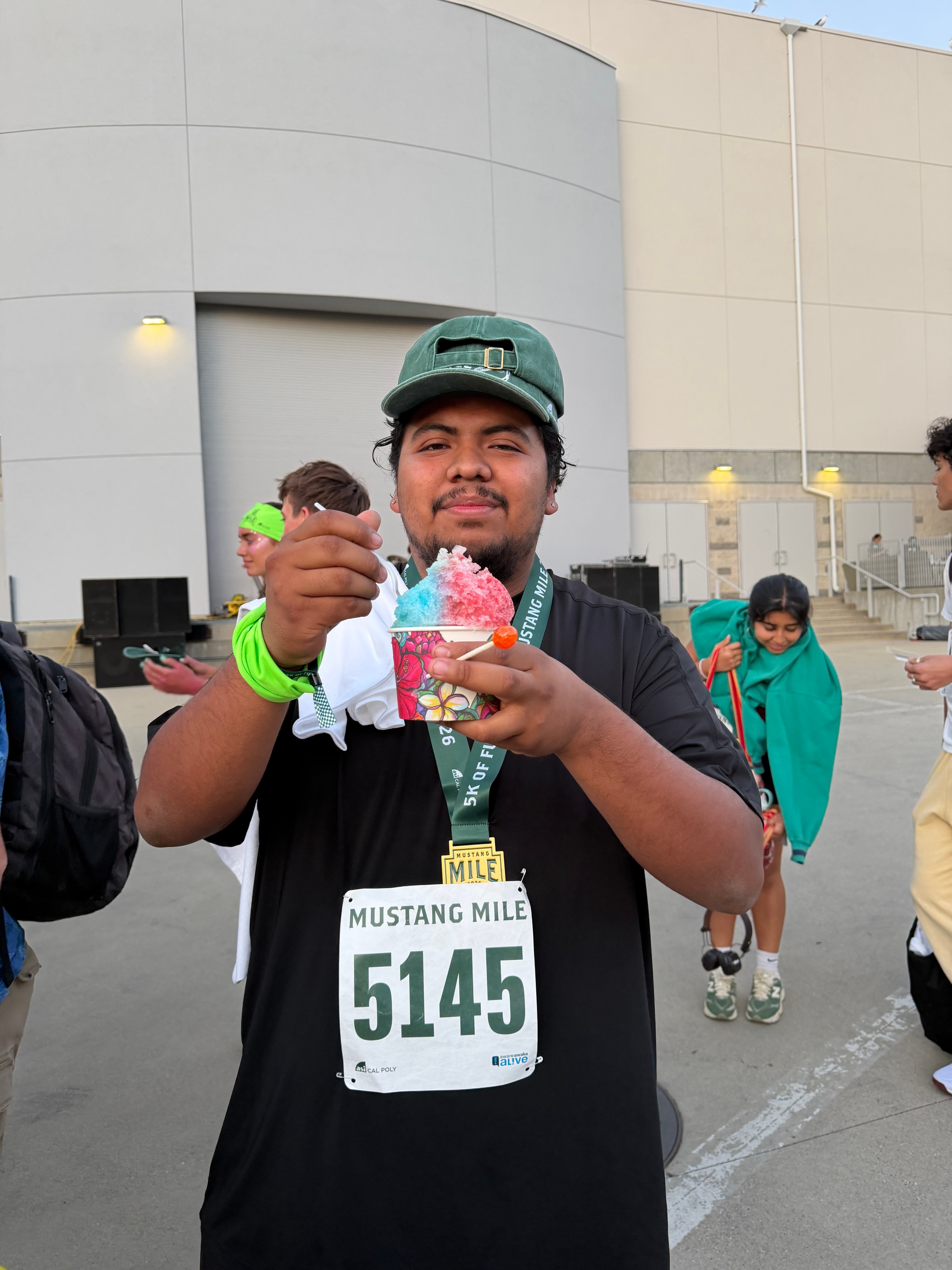 Mustang Mile runner holding up a colorful shave ice at the Shaka Shak booth