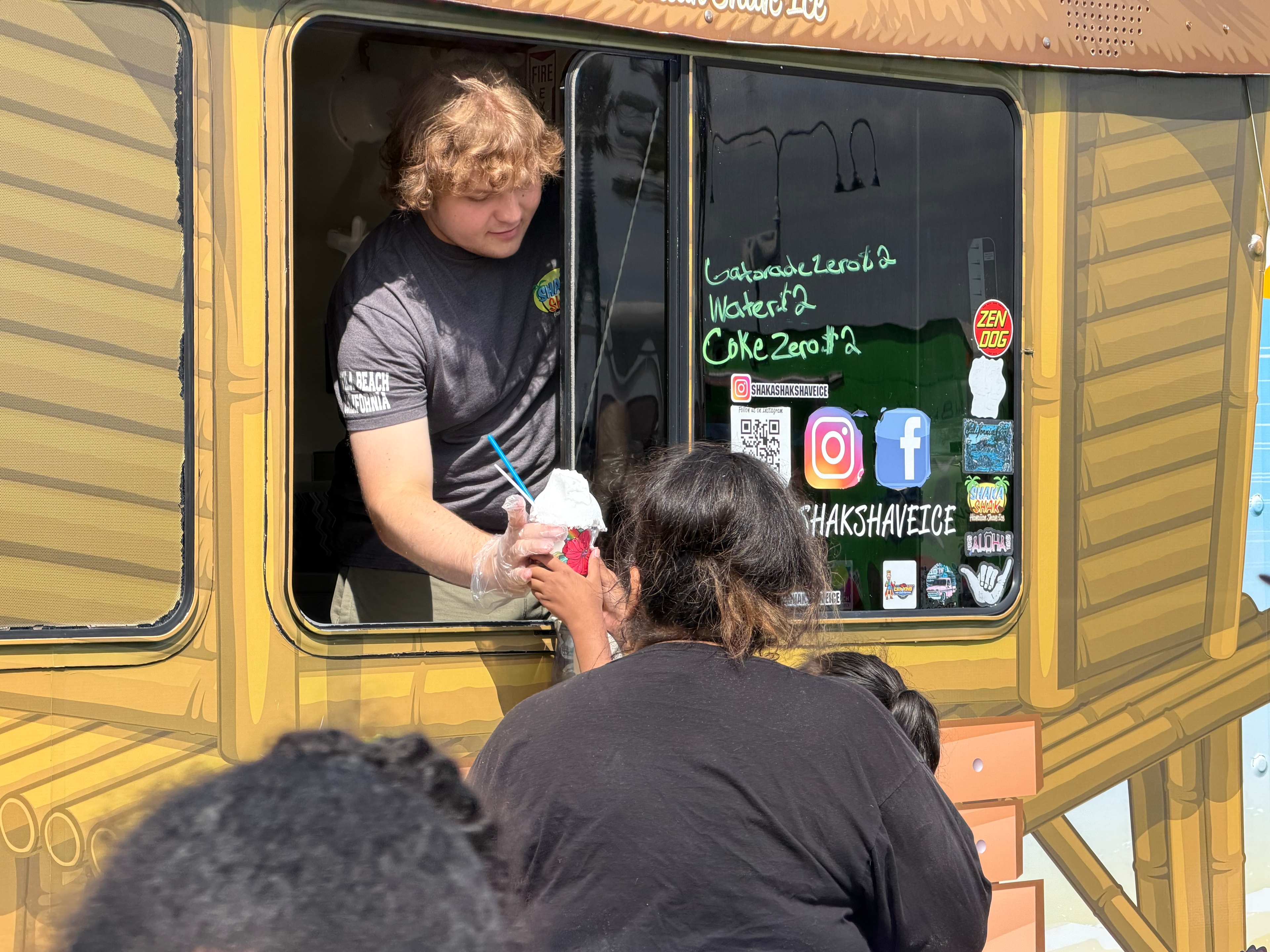 Shaka Shak staff member handing shave ice out the truck window to a customer